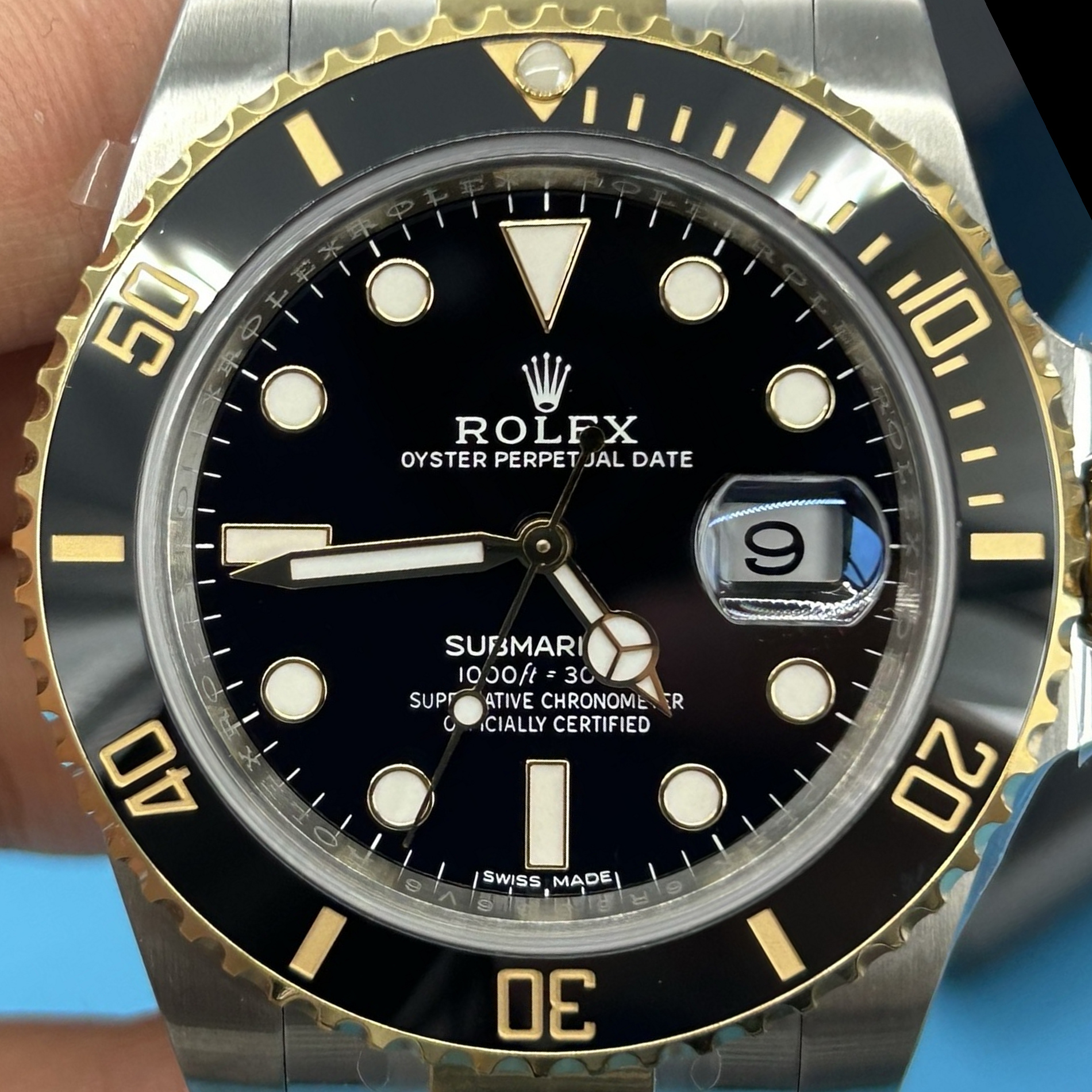 S010 · Camera geometry corrected. Image rotated approximately 26.8° counterclockwise at the dial centre; perspective and unequal image scaling normalized to a circular dial reference using detected printed tick centres. Recentered and resampled to 1900 × 1900 pixels. No correction for crystal refraction or raised bezel/hand geometry. Extended rays are visual dial references only; they do not correct or measure the raised bezel.